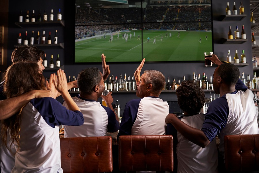 People in a sports bar watching a game on a video wall display. 