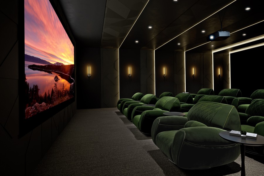 A luxury home theater with lights dimmed and screen turned on to a sunset image. 