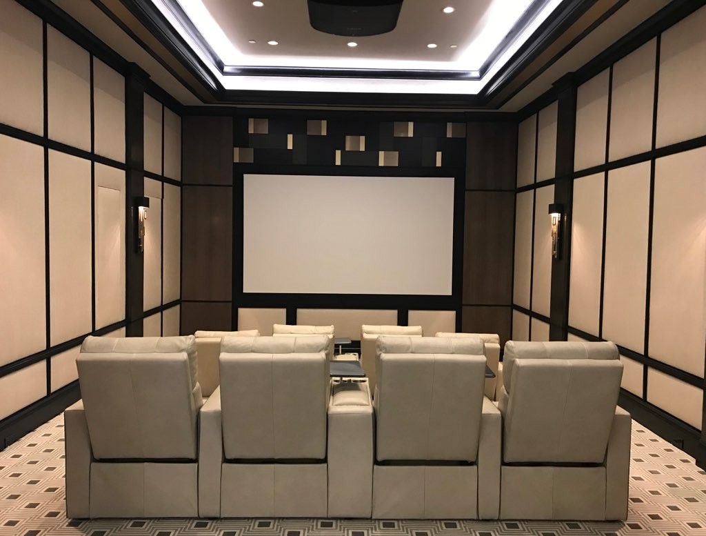 A home theater with white seating, white acoustic panels, and linear ceiling lighting.