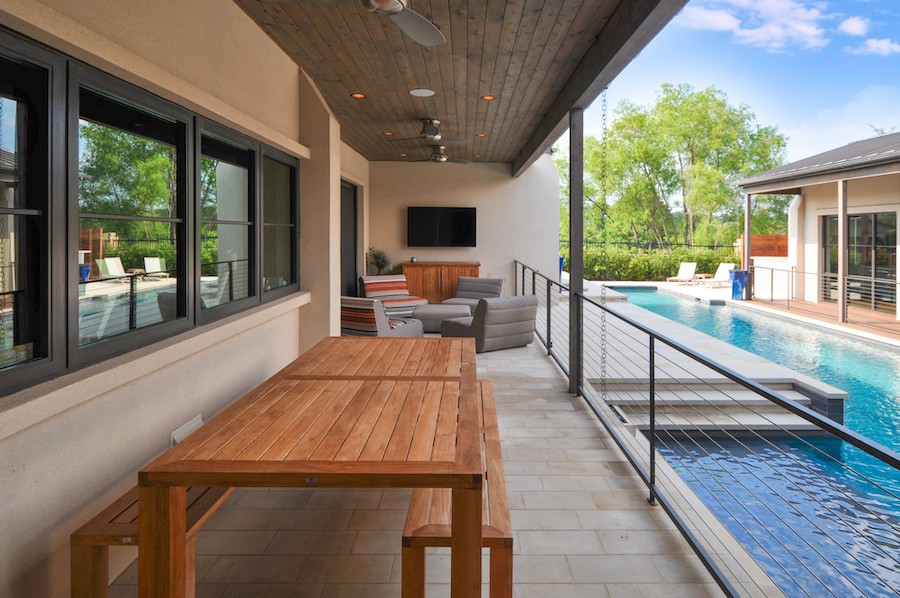  A covered porch by a pool with in-ceiling speakers. 