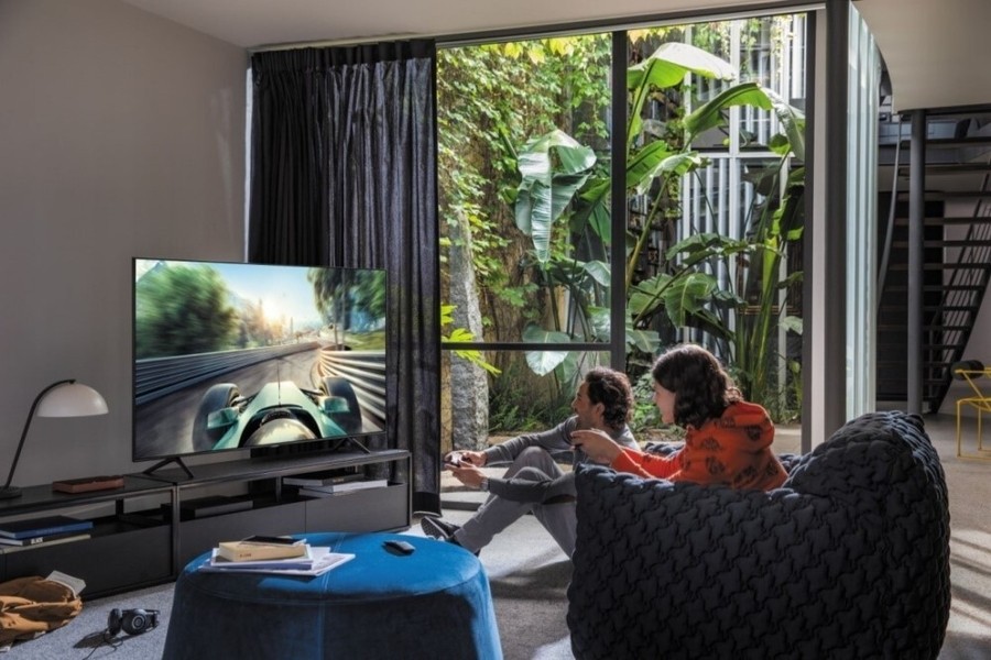 Two people in a living room playing video games on a Samsung TV. 