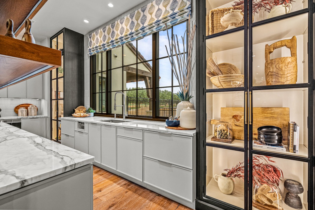 A kitchen with patterned motorized shades lowered a quarter down windows.