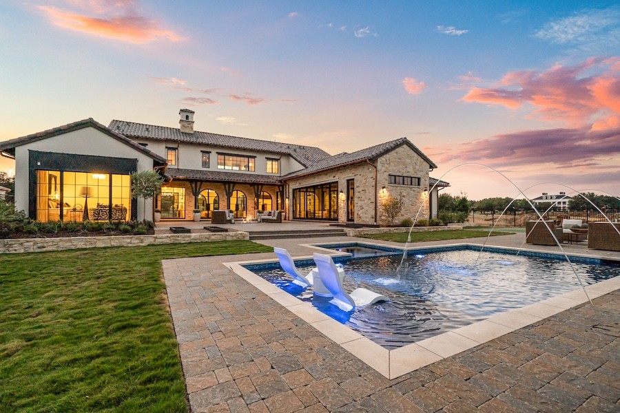 Modern backyard scene at sunset with downlighting on stone walls.
