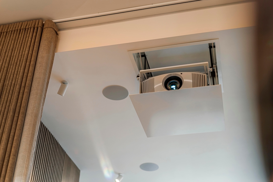 A home theater ceiling with a projector lift, in-ceiling speaker, and track lighting.