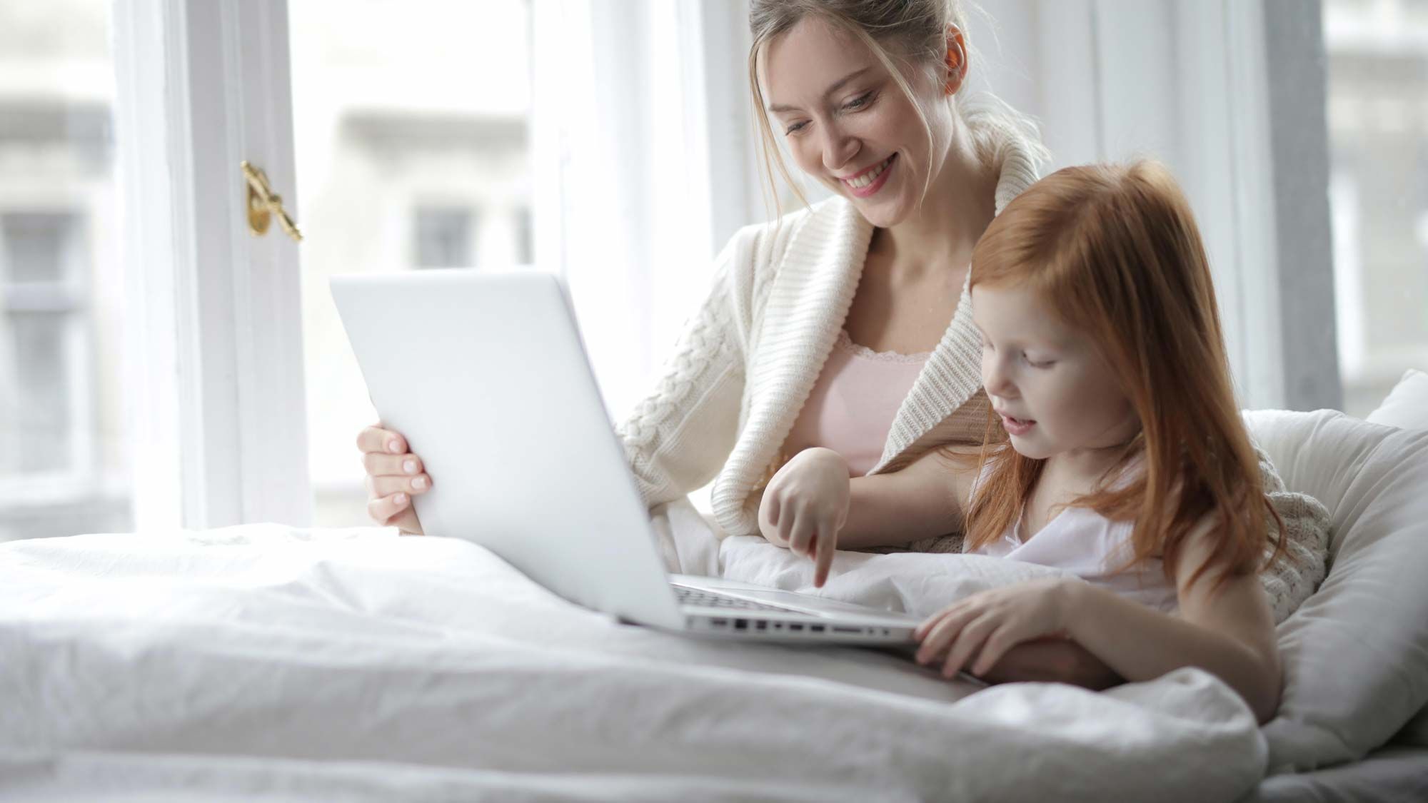 mom and daughter playing on laptop together